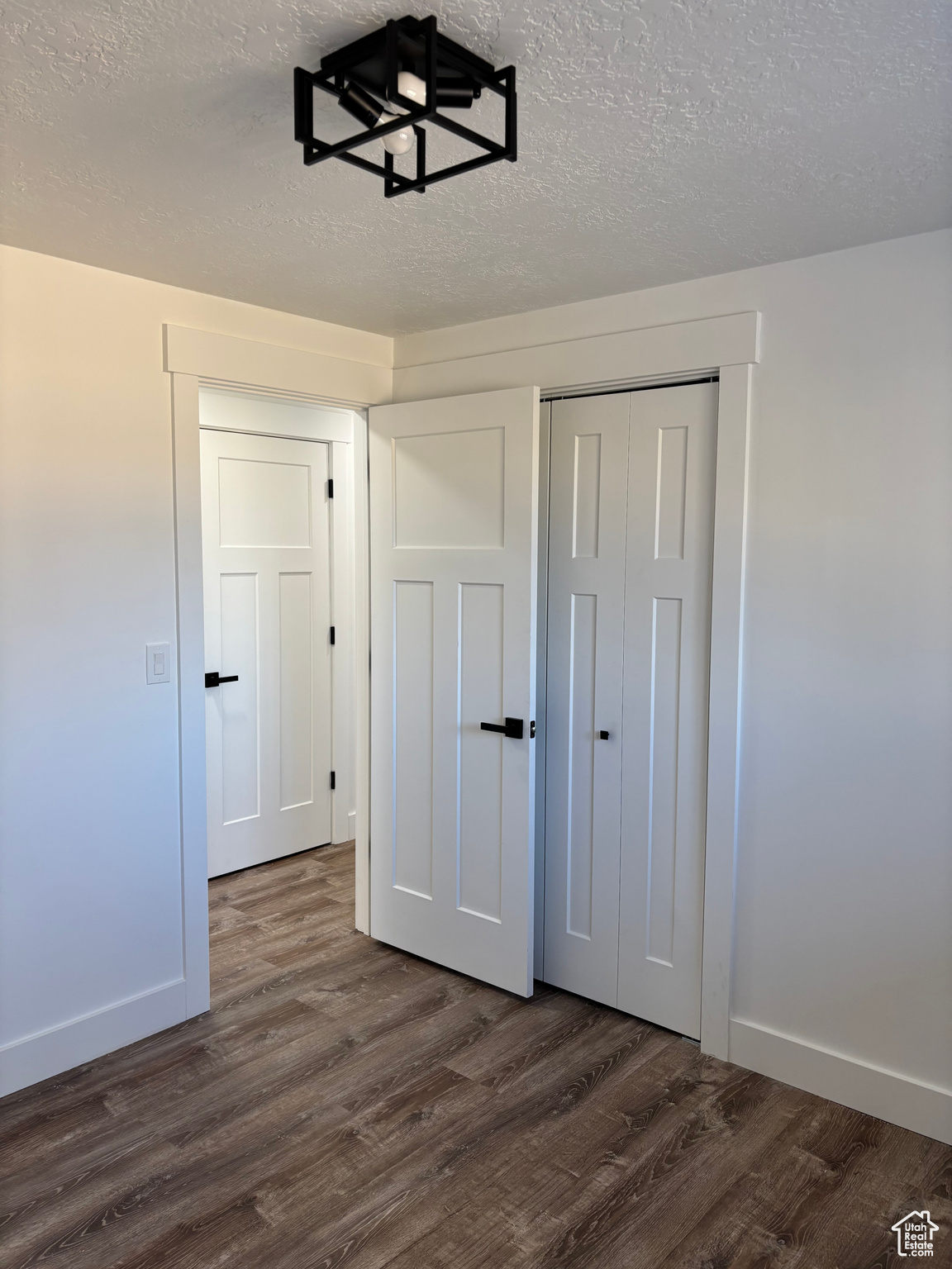 Unfurnished bedroom featuring a closet, dark wood-type flooring, and a textured ceiling