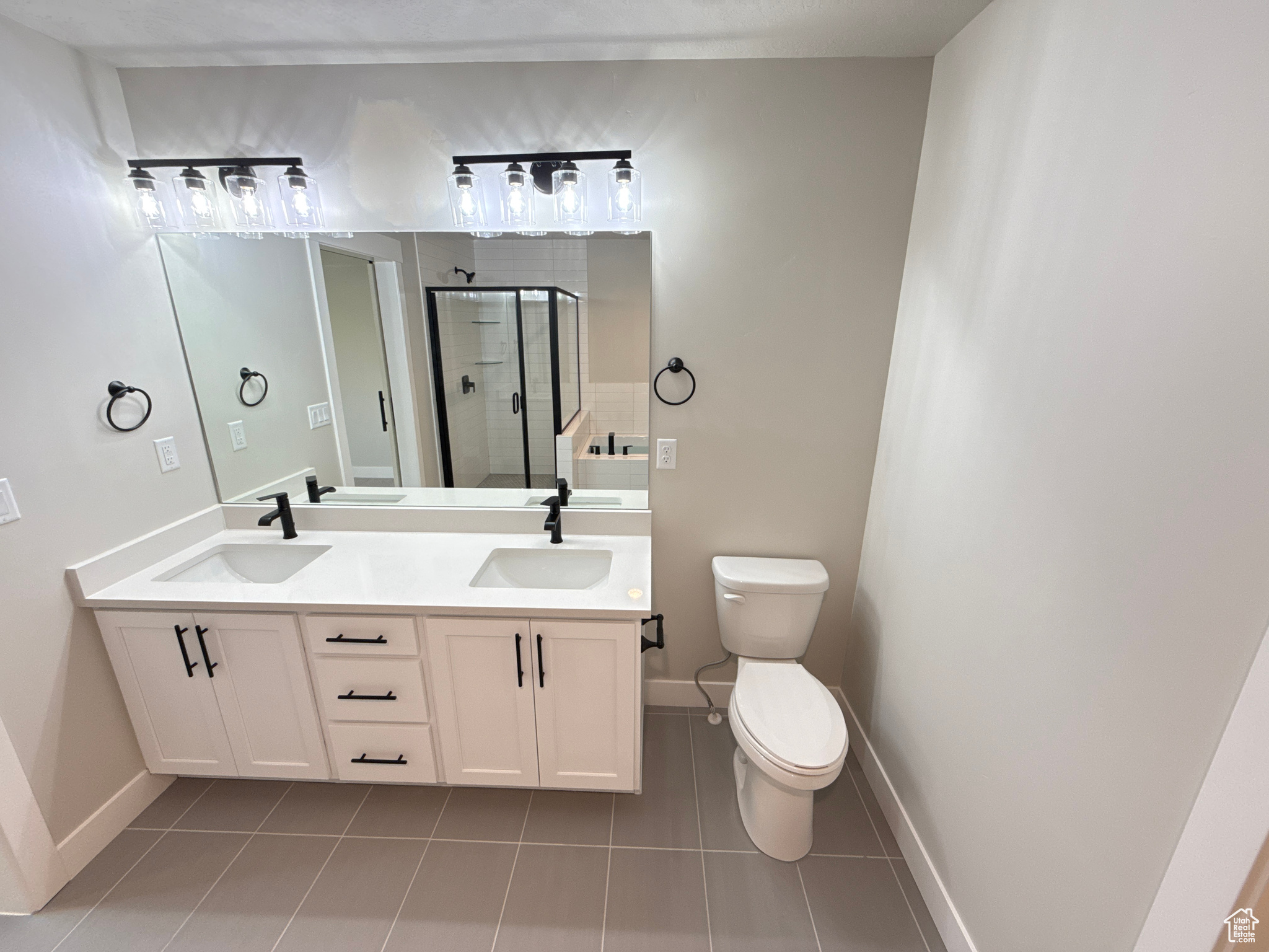 Primary bathroom with tile patterned floors, vanity, toilet, and an enclosed shower