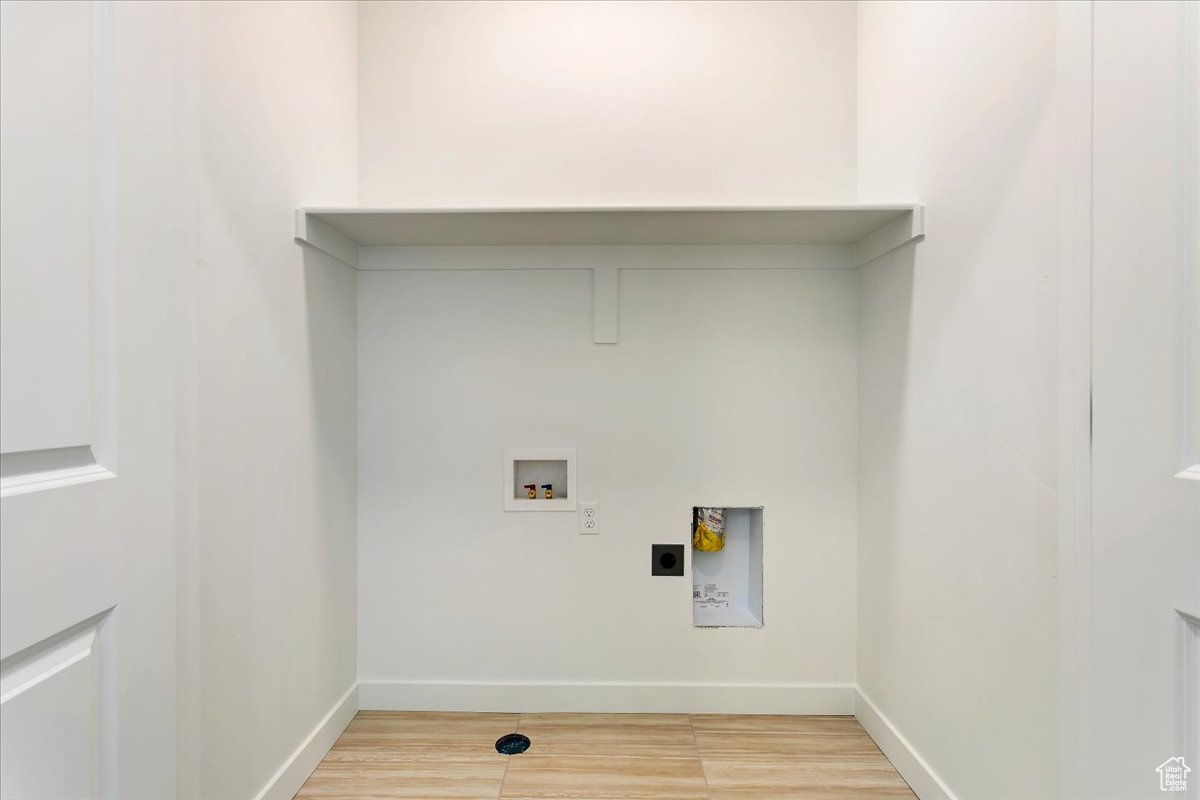 Washroom with hookup for an electric dryer, washer hookup, and hardwood / wood-style flooring