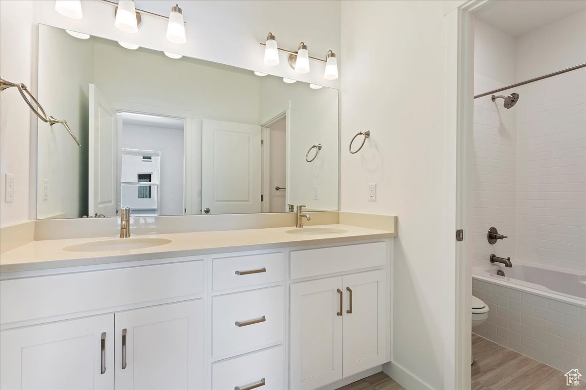 Full bathroom featuring wood-type flooring, vanity, toilet, and tiled shower / bath