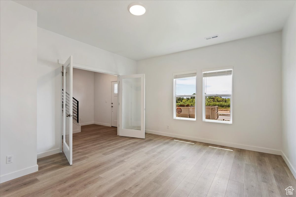 Unfurnished bedroom featuring french doors and light hardwood / wood-style flooring