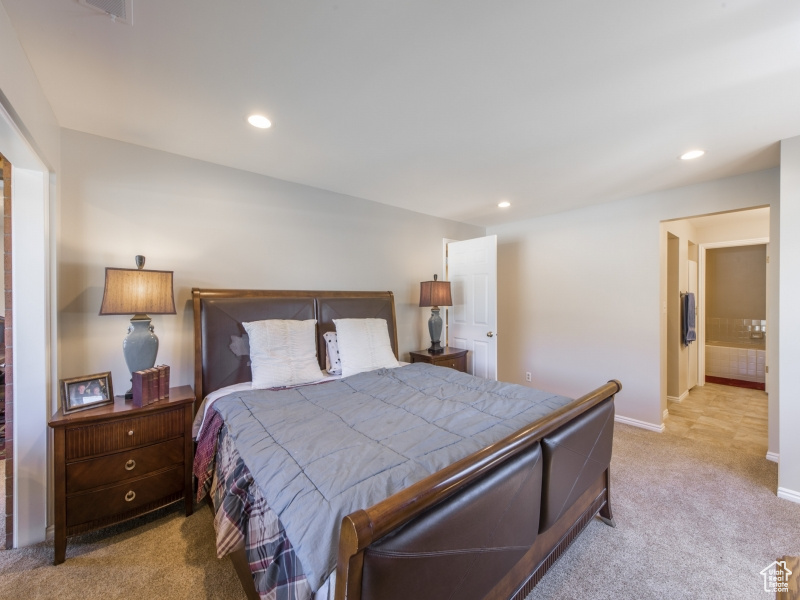 Bedroom featuring light colored carpet and ensuite bath