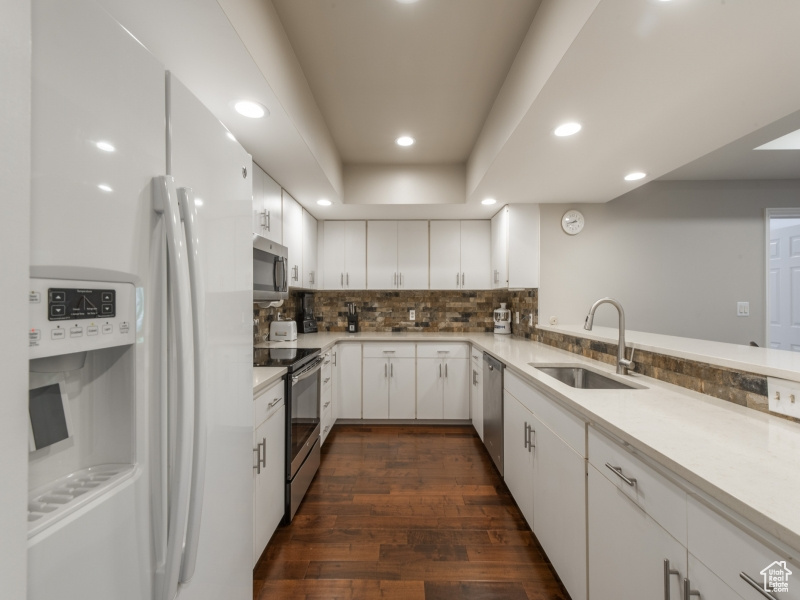 Kitchen with stainless steel appliances, white cabinetry, dark hardwood / wood-style floors, and sink