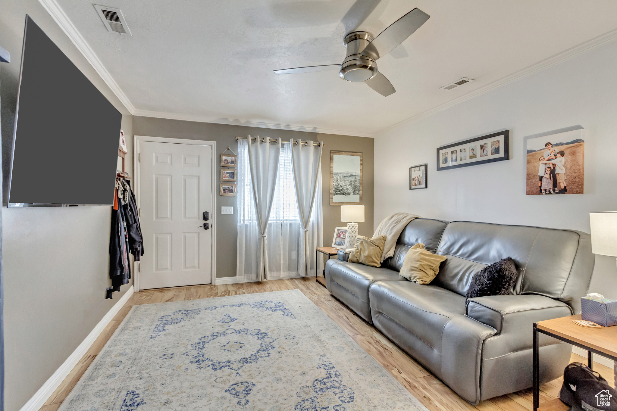 Living room with ceiling fan, ornamental molding, and light wood-type flooring