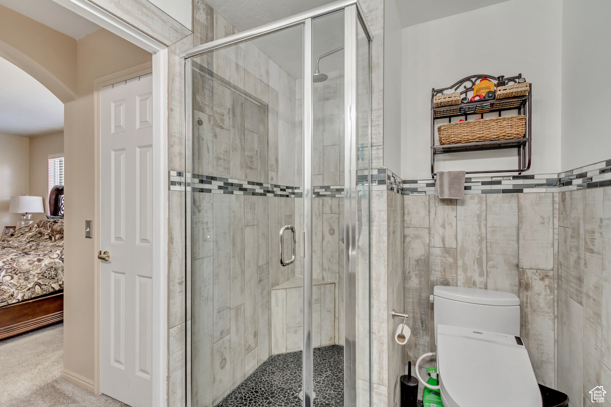 Bathroom featuring tile walls, an enclosed shower, and toilet