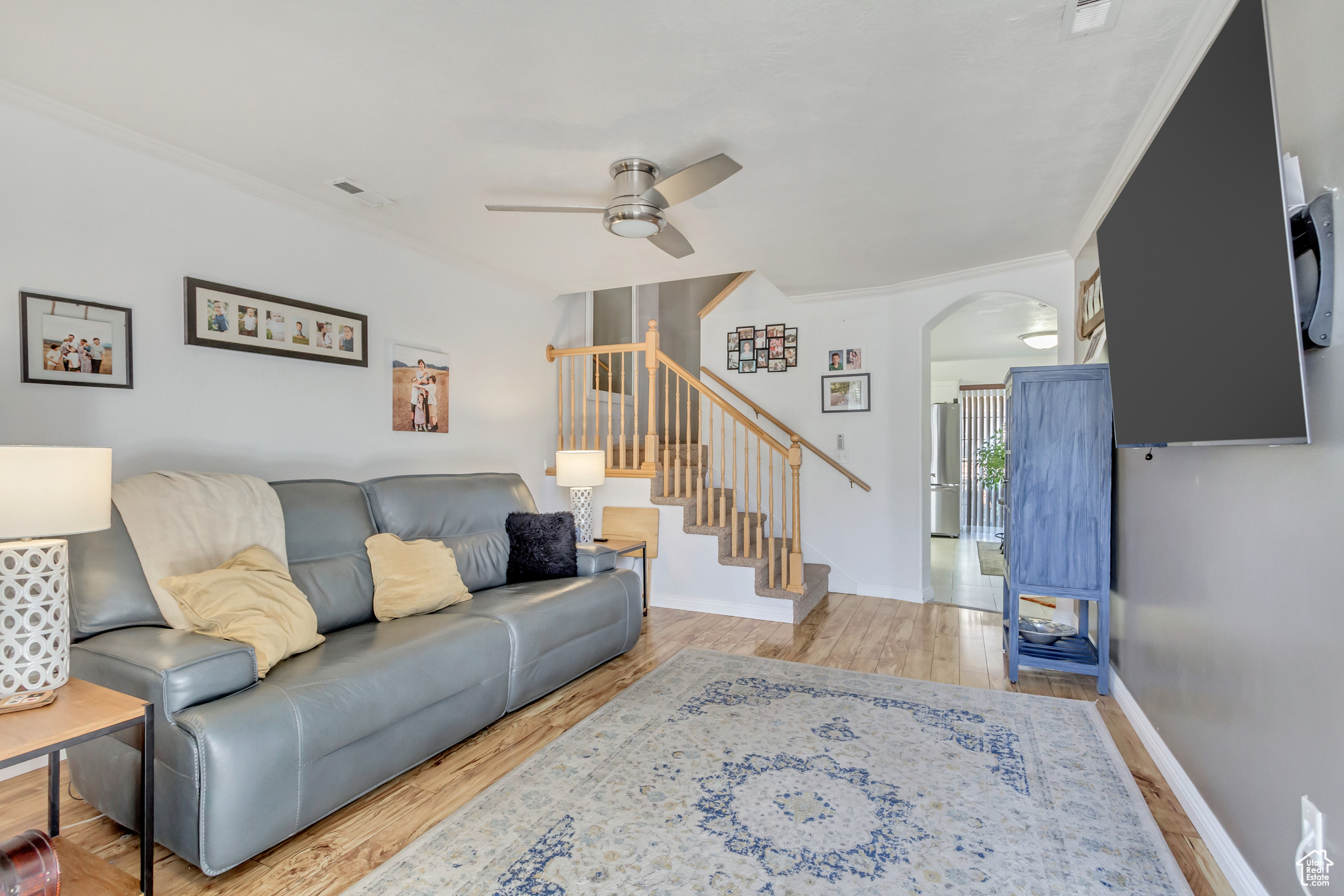 Living room featuring crown molding, ceiling fan, and light hardwood / wood-style floors