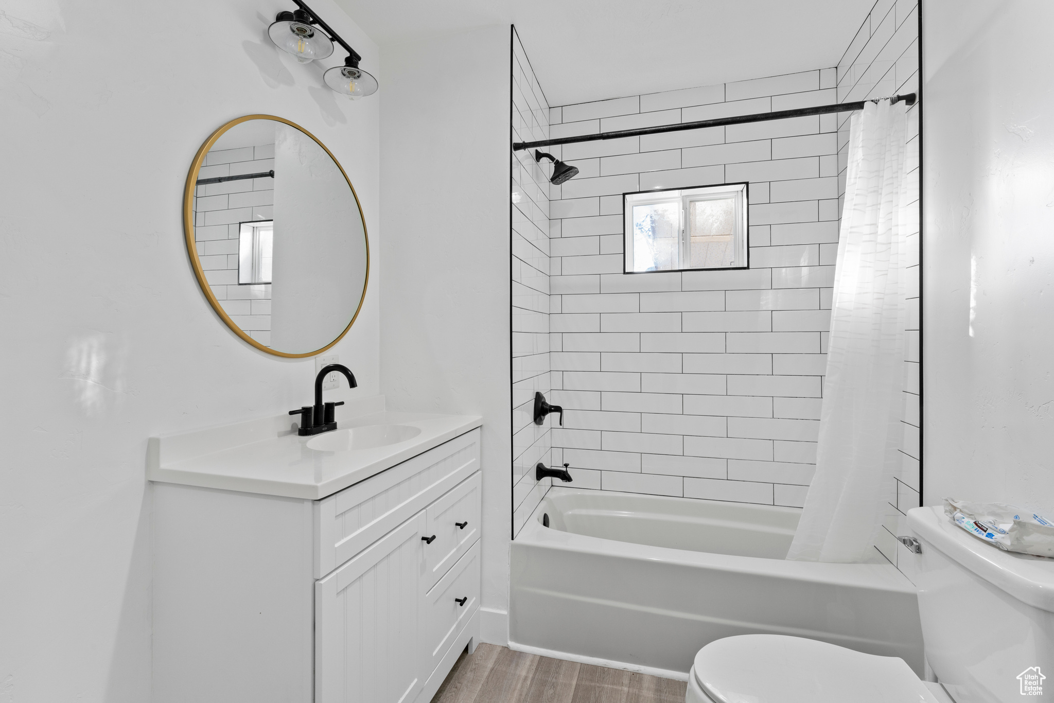 Full bathroom featuring toilet, shower / tub combo with curtain, vanity, and hardwood / wood-style flooring