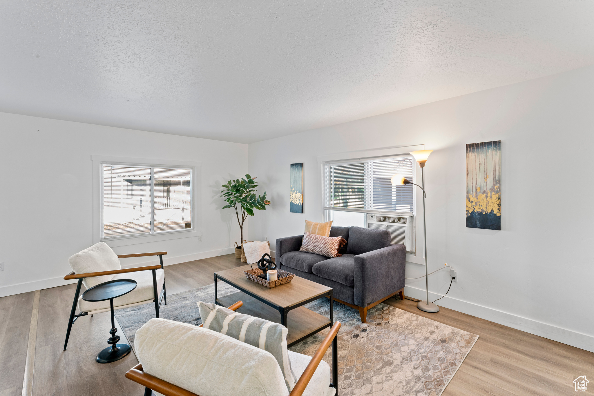 Living room with cooling unit, a textured ceiling, and light hardwood / wood-style flooring