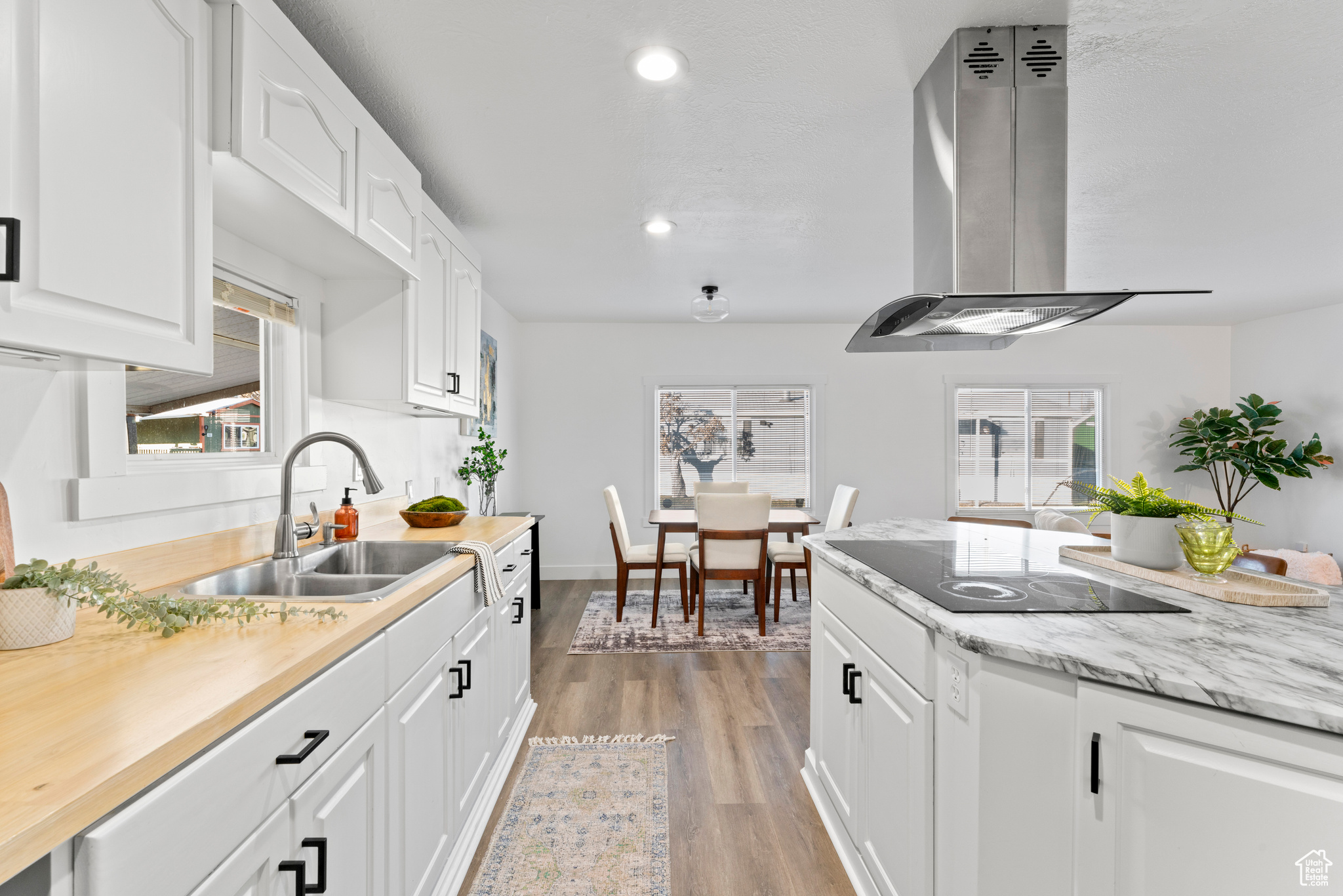 Kitchen featuring a healthy amount of sunlight, light wood-type flooring, white cabinetry, and range hood