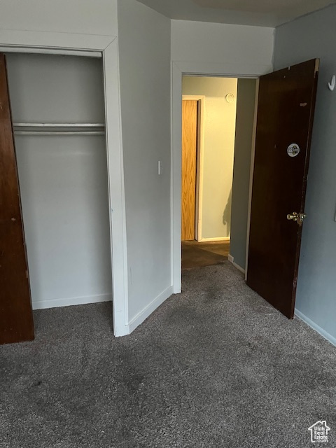 Unfurnished bedroom featuring dark carpet and a closet