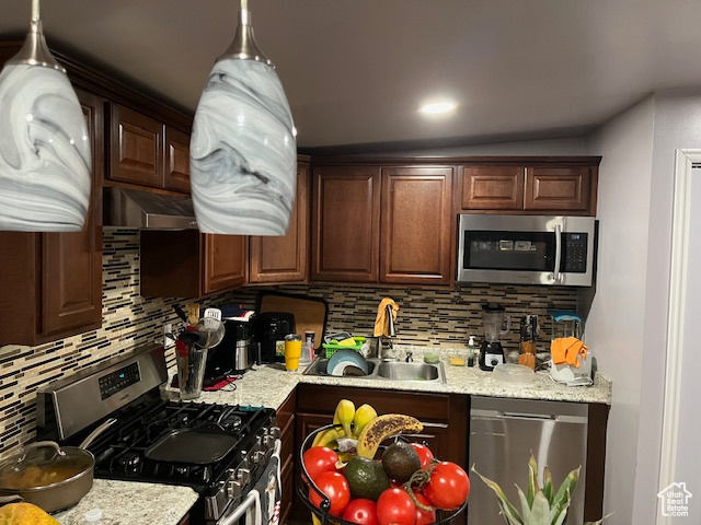 Kitchen with decorative backsplash, sink, stainless steel appliances, and dark brown cabinets