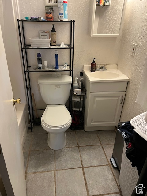 Bathroom with tile patterned floors, vanity, a tub to relax in, and toilet