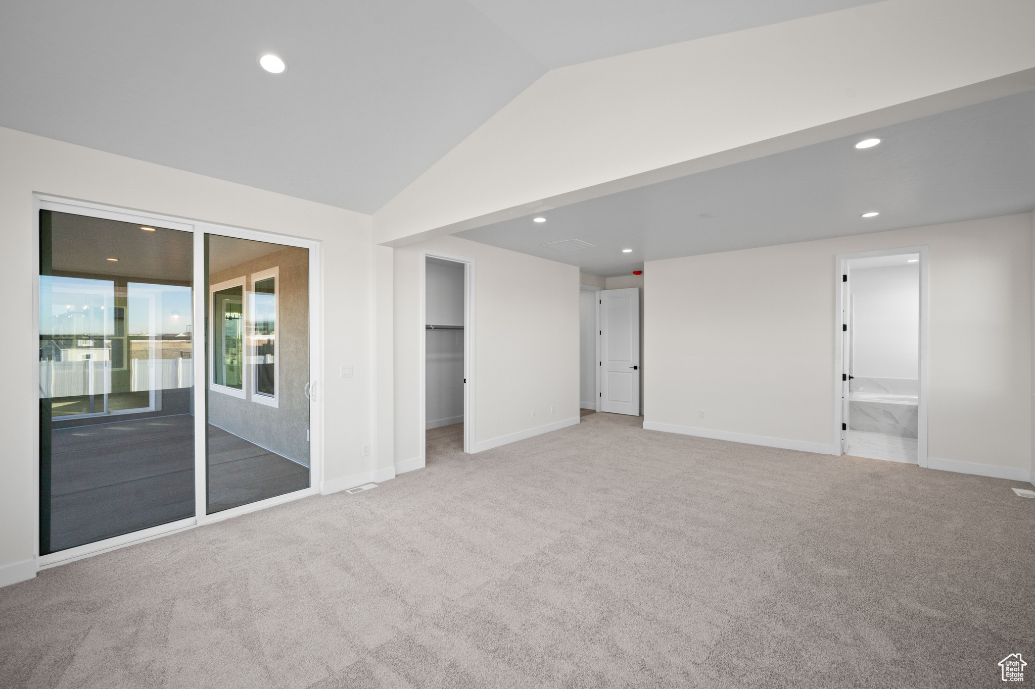 Empty room featuring light colored carpet and lofted ceiling