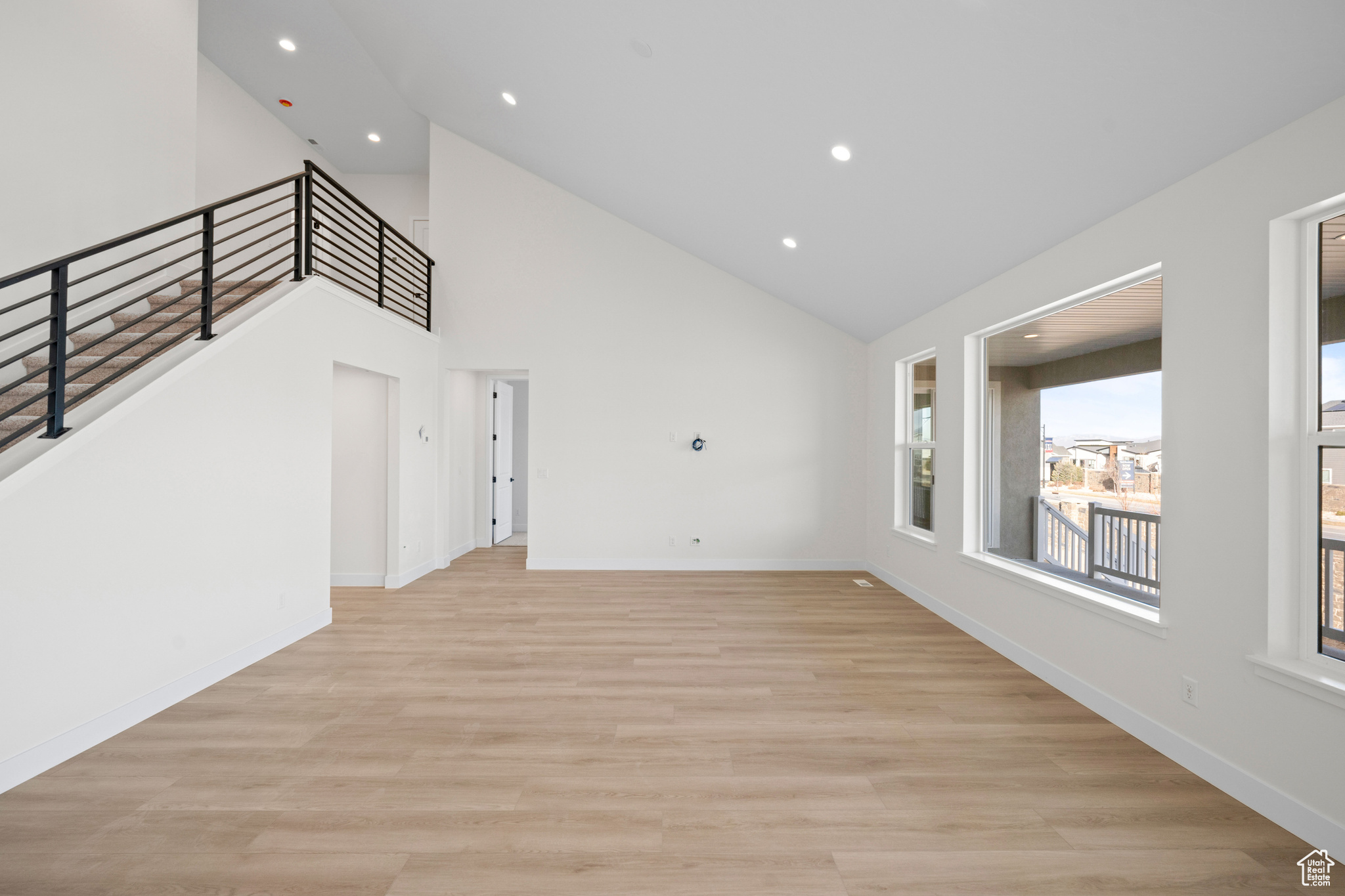 Unfurnished living room with light hardwood / wood-style floors and high vaulted ceiling