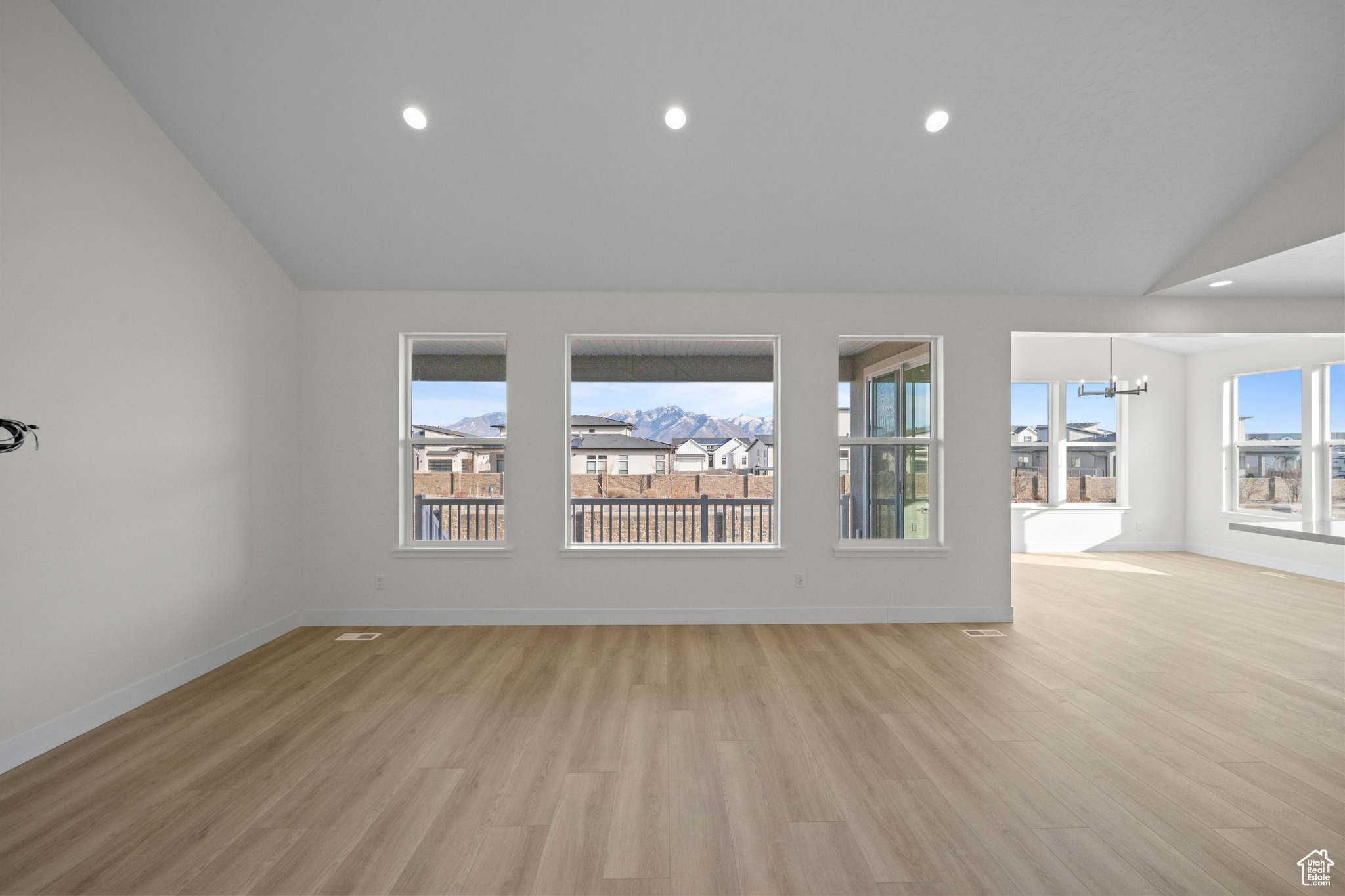 Spare room featuring light hardwood / wood-style flooring, lofted ceiling, and an inviting chandelier