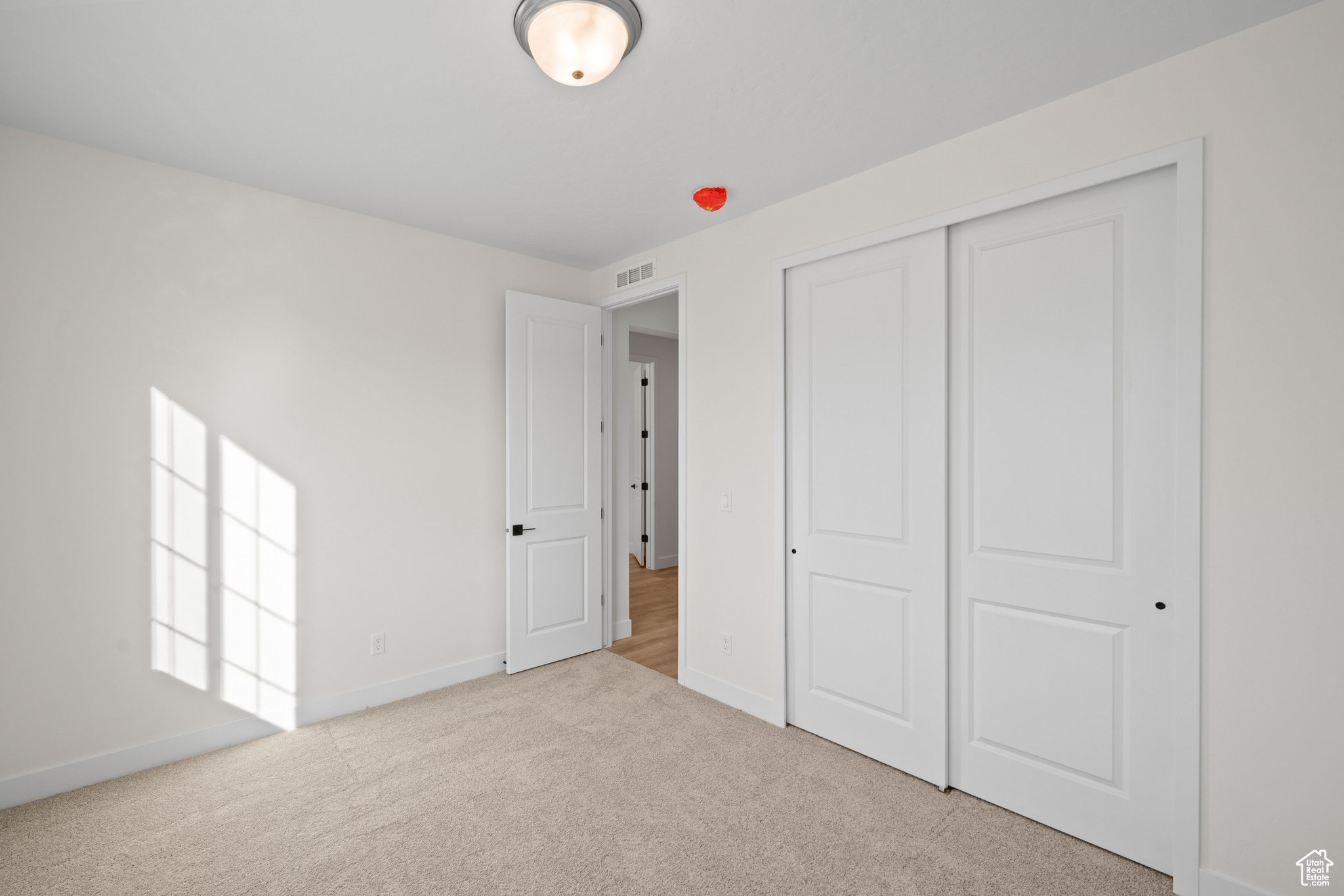 Unfurnished bedroom with a closet and light colored carpet