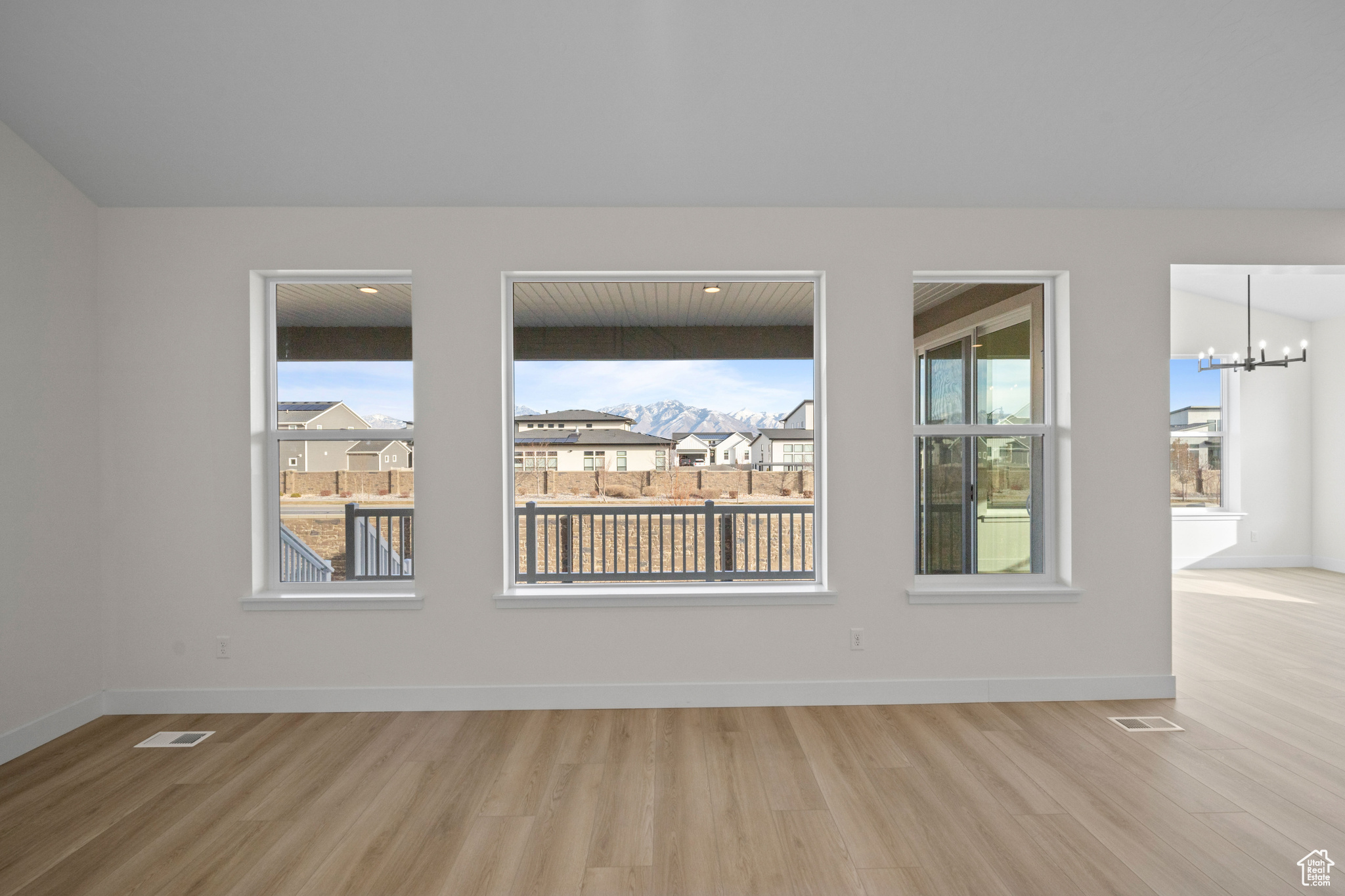 Unfurnished room with wood-type flooring and a notable chandelier