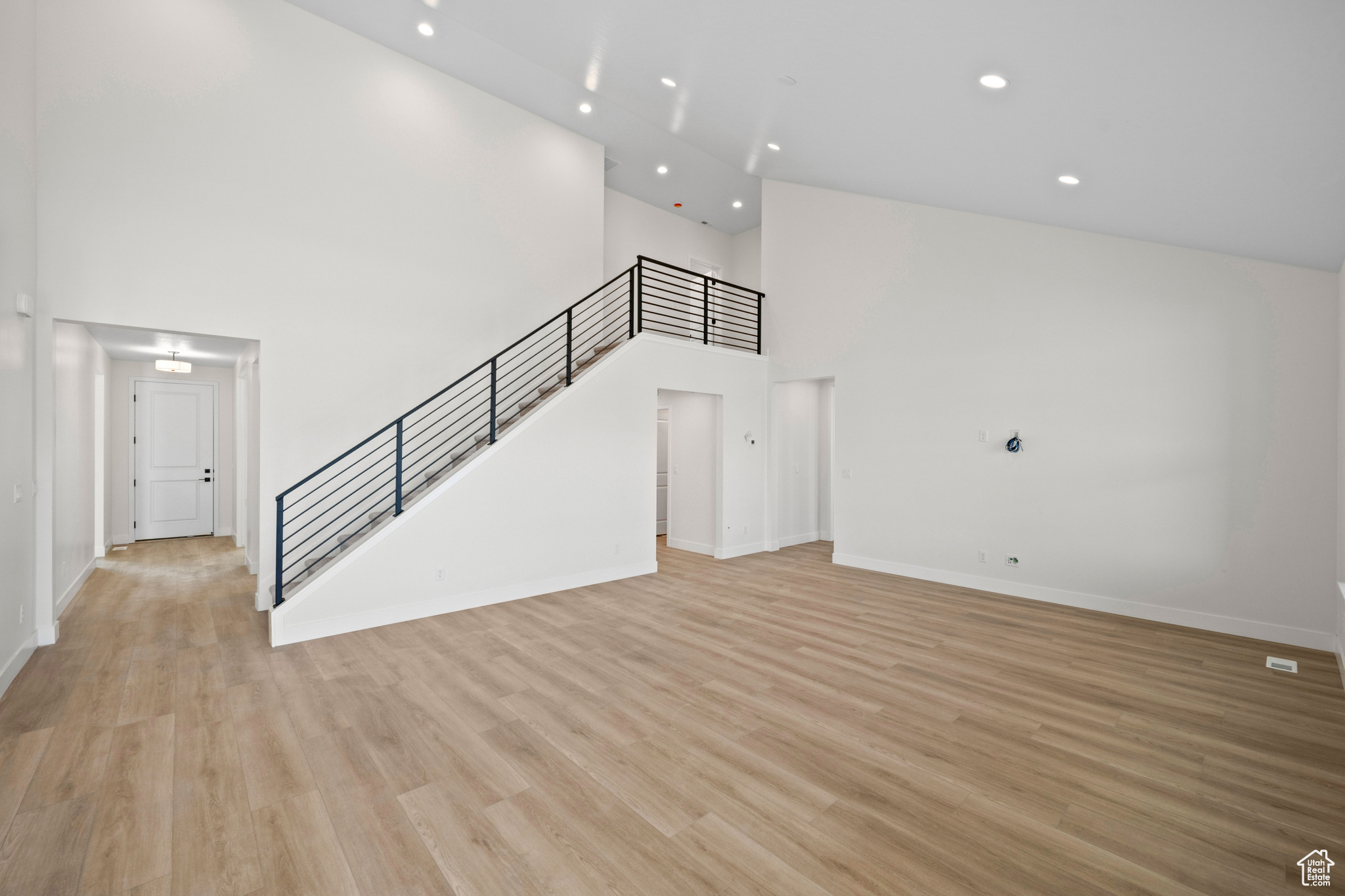 Unfurnished living room with a towering ceiling and light hardwood / wood-style floors