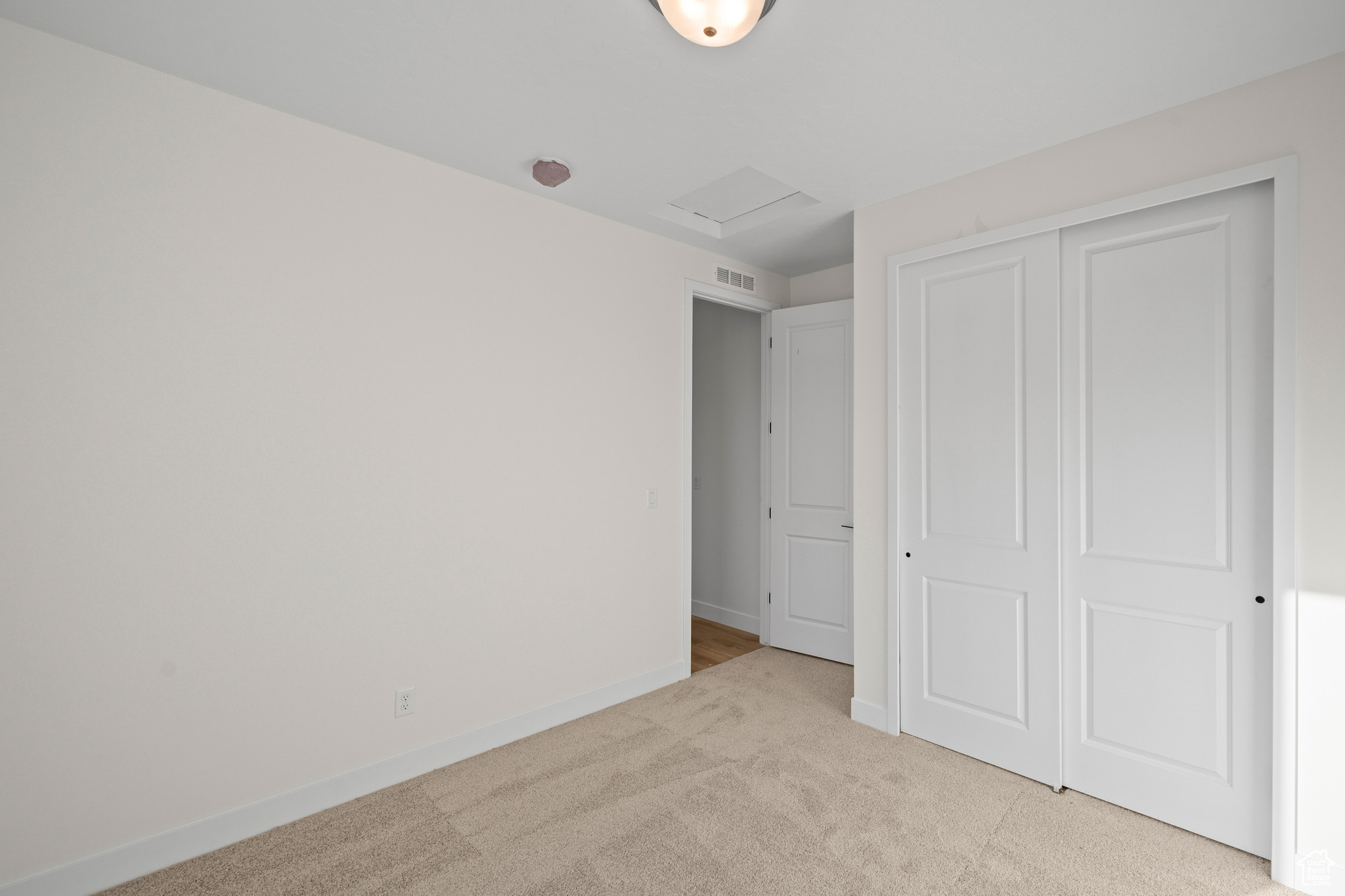 Unfurnished bedroom featuring light carpet and a closet