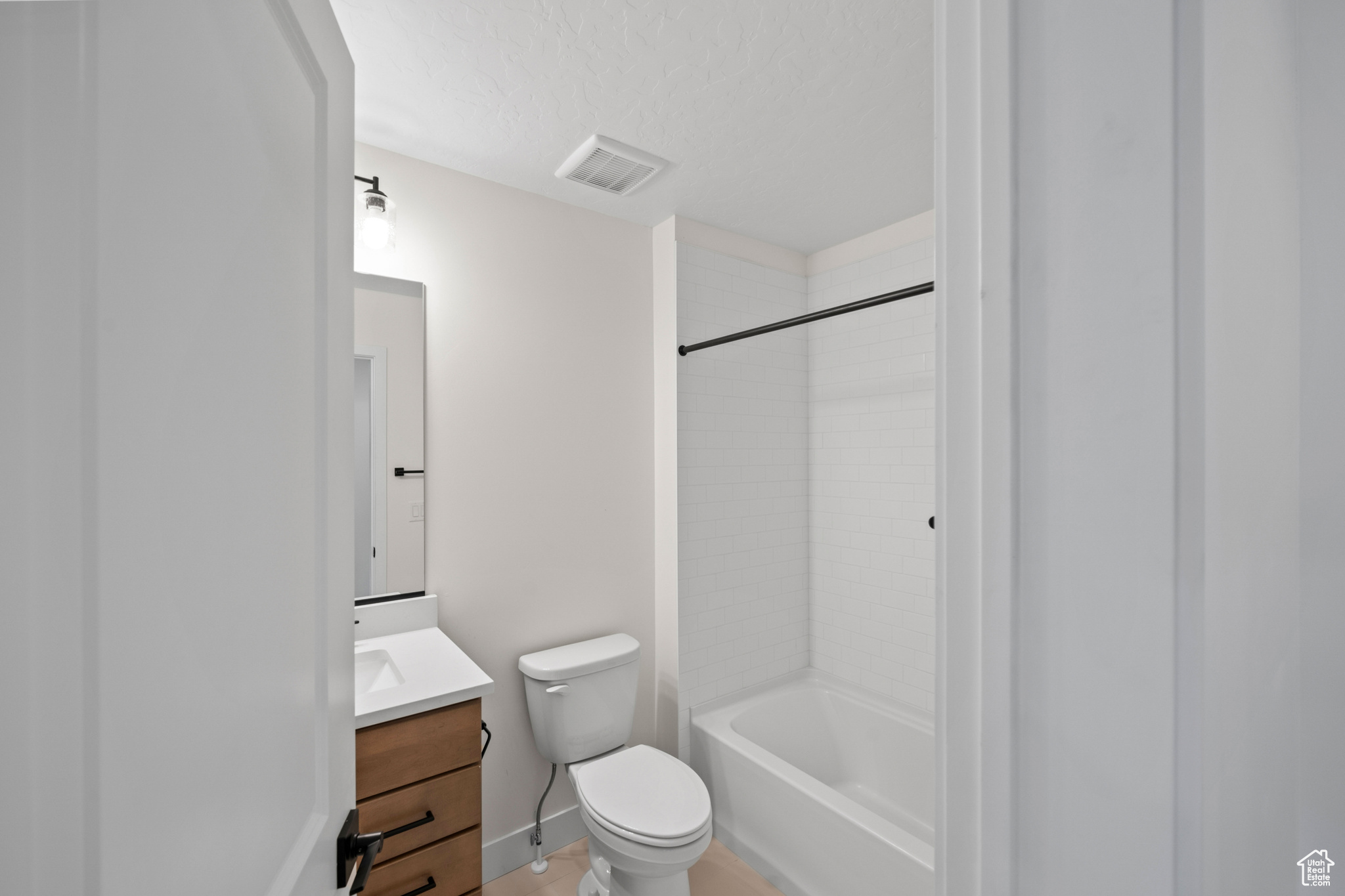 Full bathroom with washtub / shower combination, a textured ceiling, vanity, and toilet