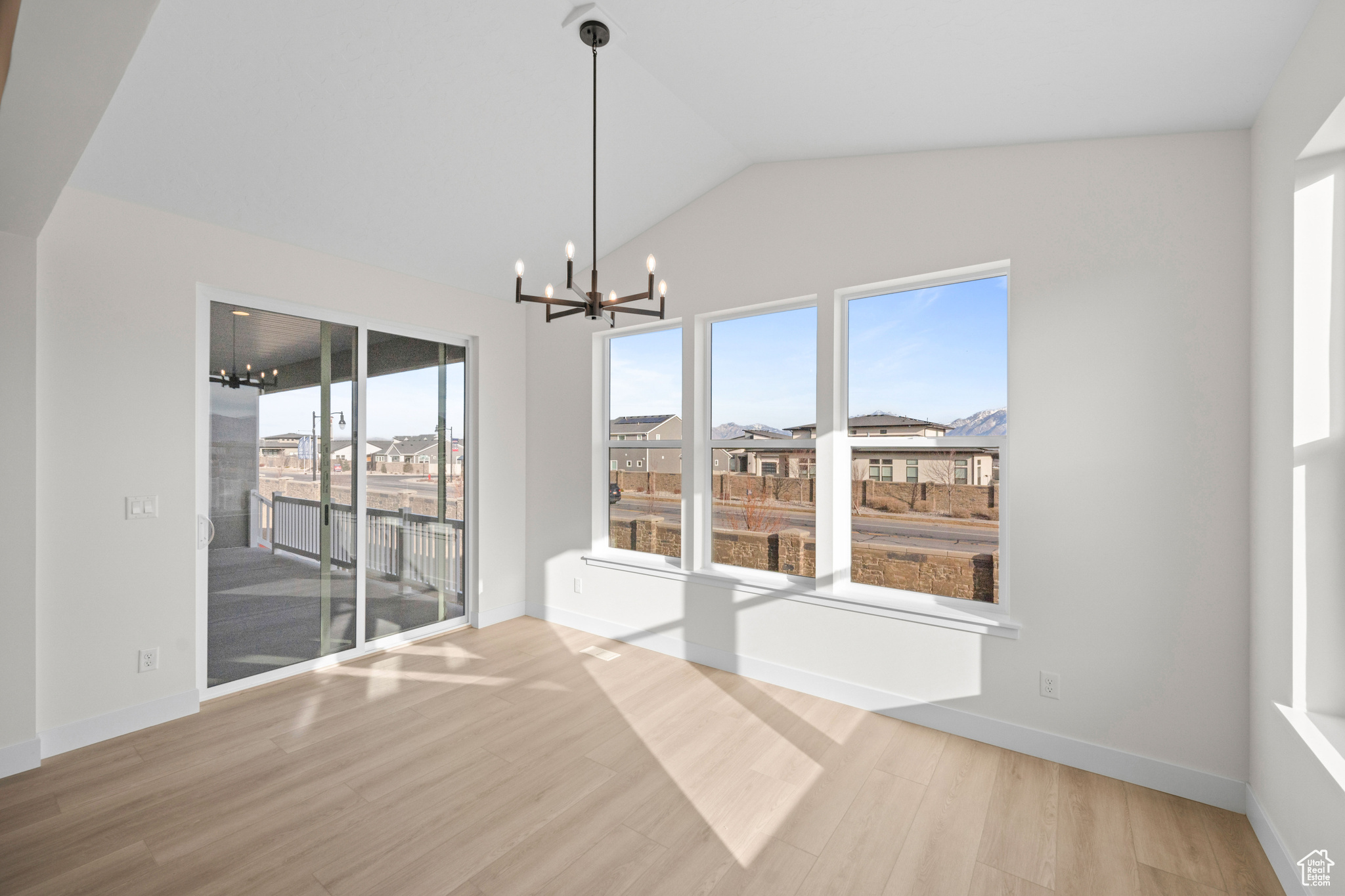 Spare room with a notable chandelier, a healthy amount of sunlight, and wood-type flooring