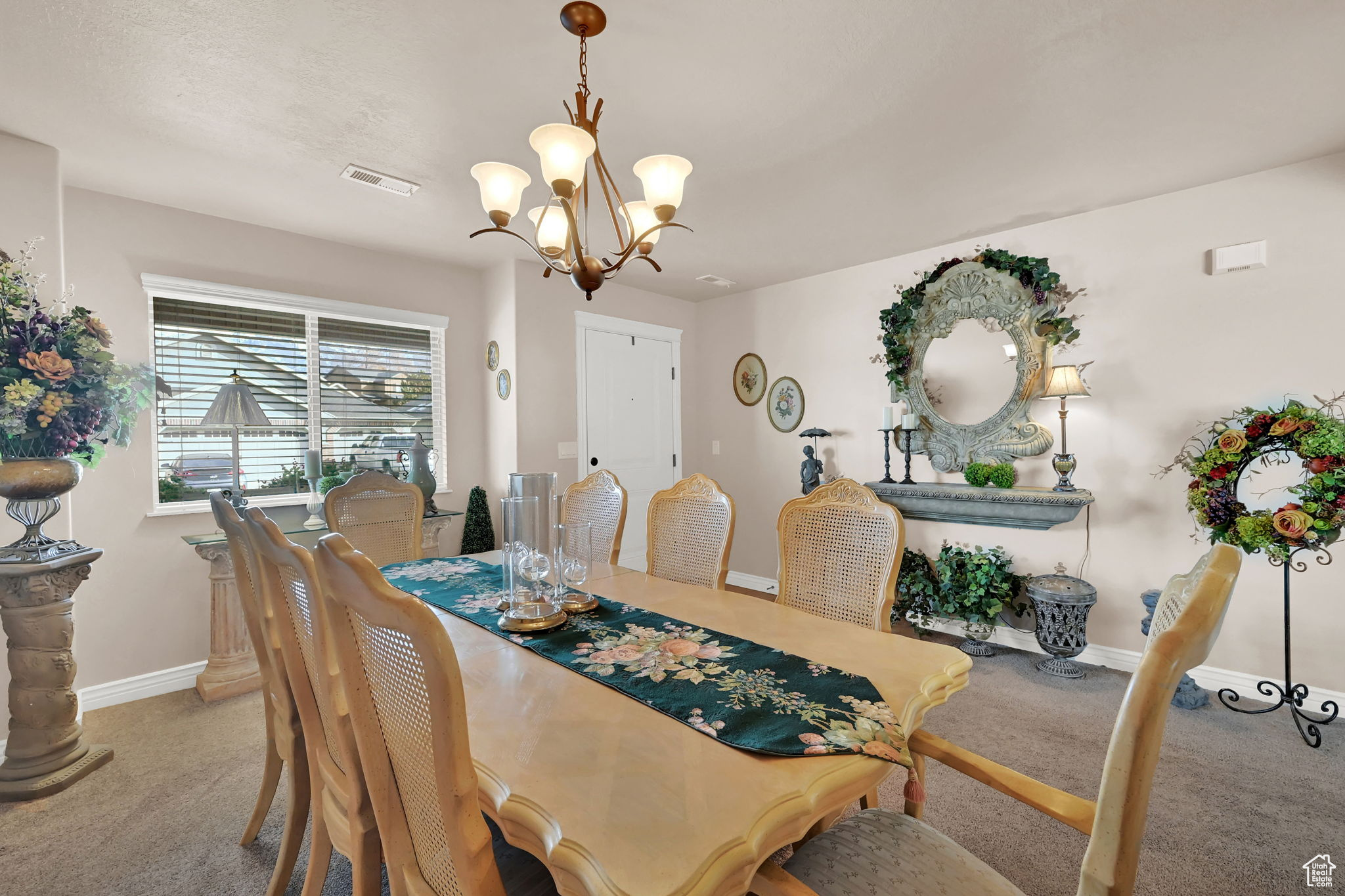 Dining space with light carpet and a chandelier