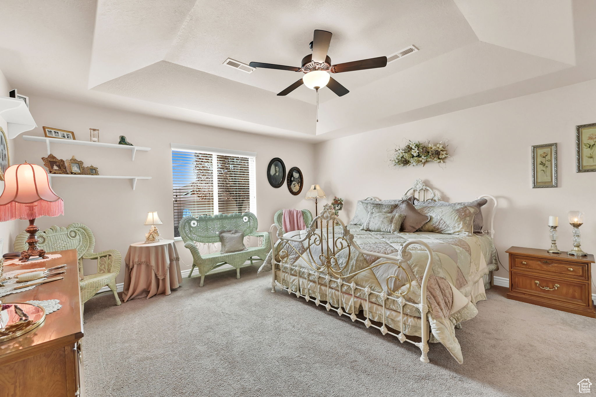 Bedroom featuring light colored carpet, a raised ceiling, and ceiling fan