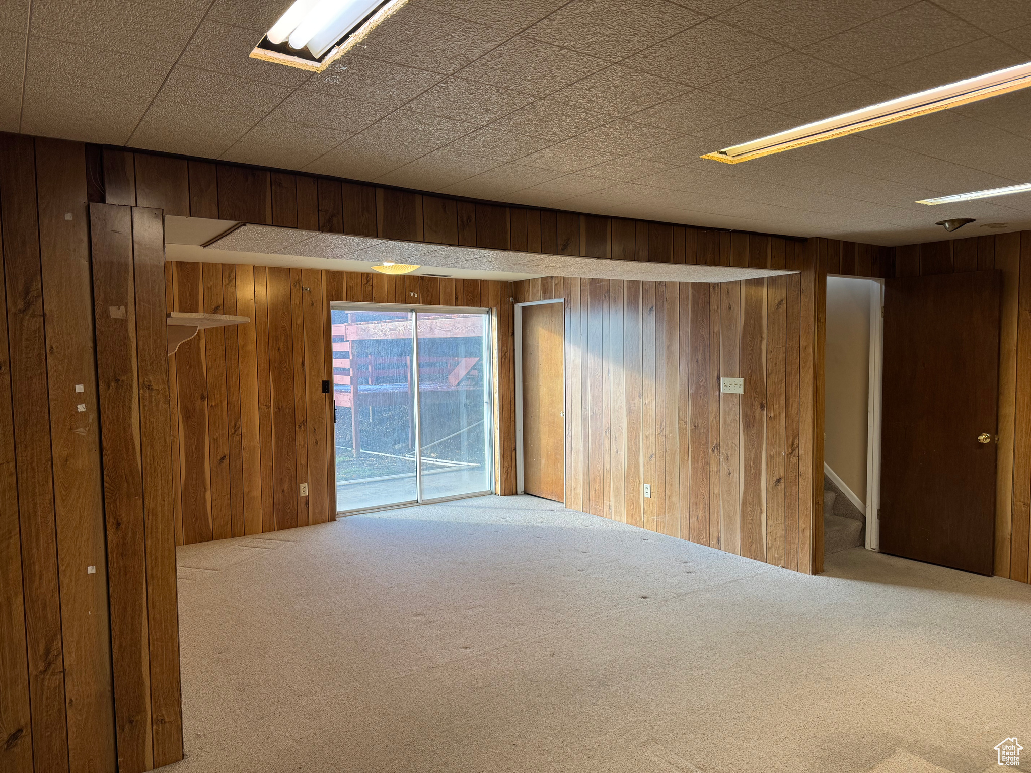 Carpeted spare room featuring wood walls