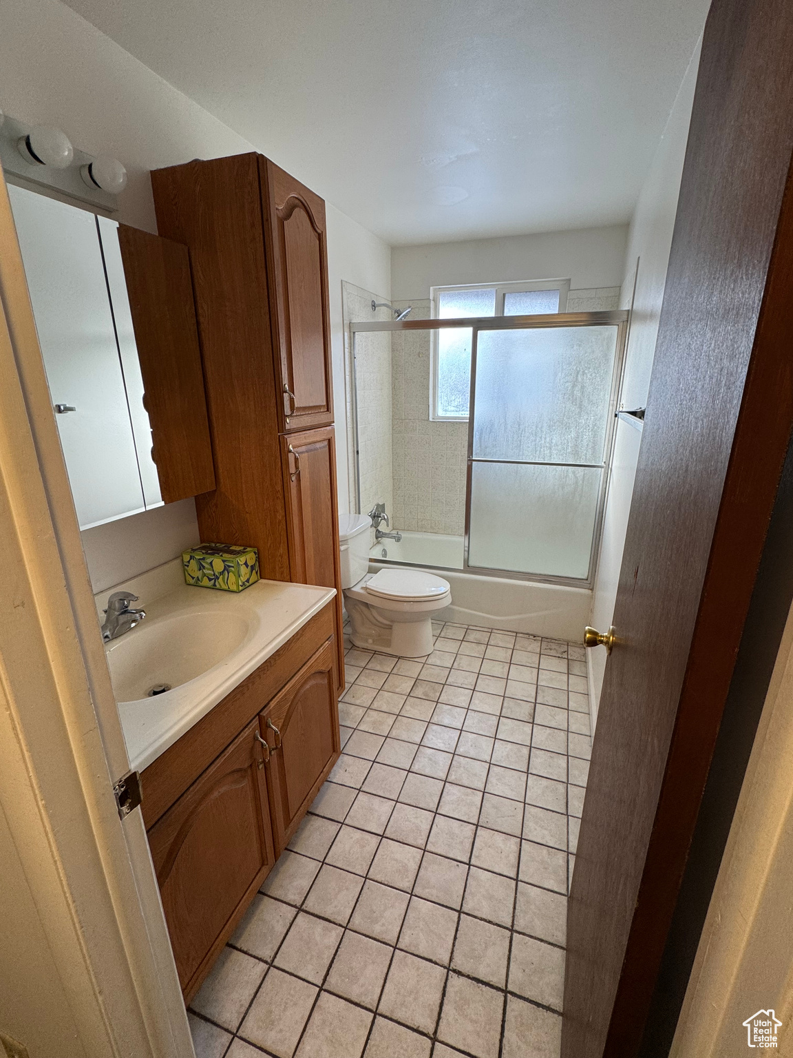 Full bathroom with toilet, tile patterned flooring, vanity, and combined bath / shower with glass door