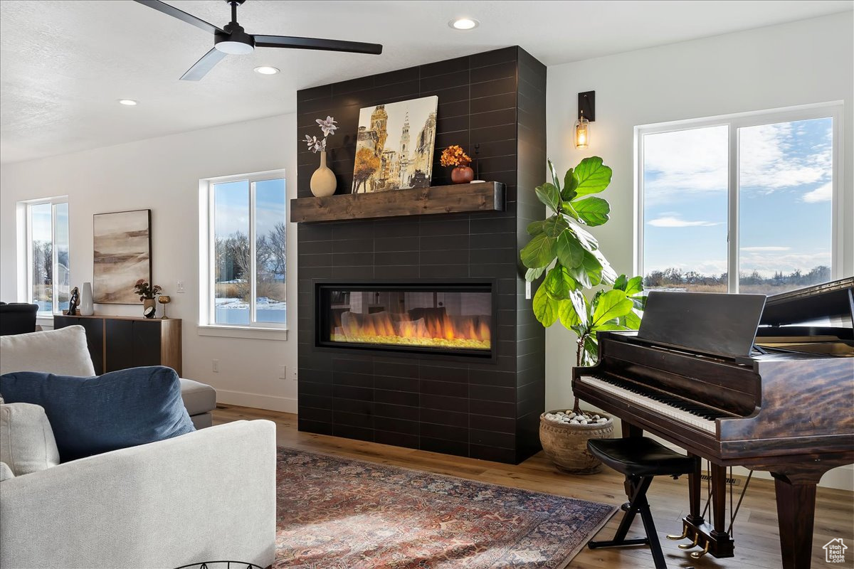 Living room featuring a large fireplace, a wealth of natural light, hardwood / wood-style floors, and ceiling fan