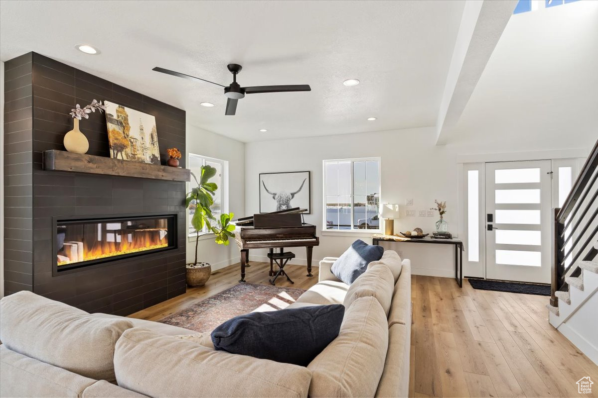 Living room featuring a fireplace, light wood-type flooring, and ceiling fan