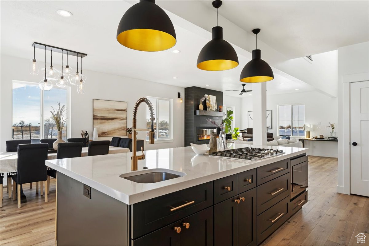 Kitchen with appliances with stainless steel finishes, decorative light fixtures, a kitchen island with sink, and sink