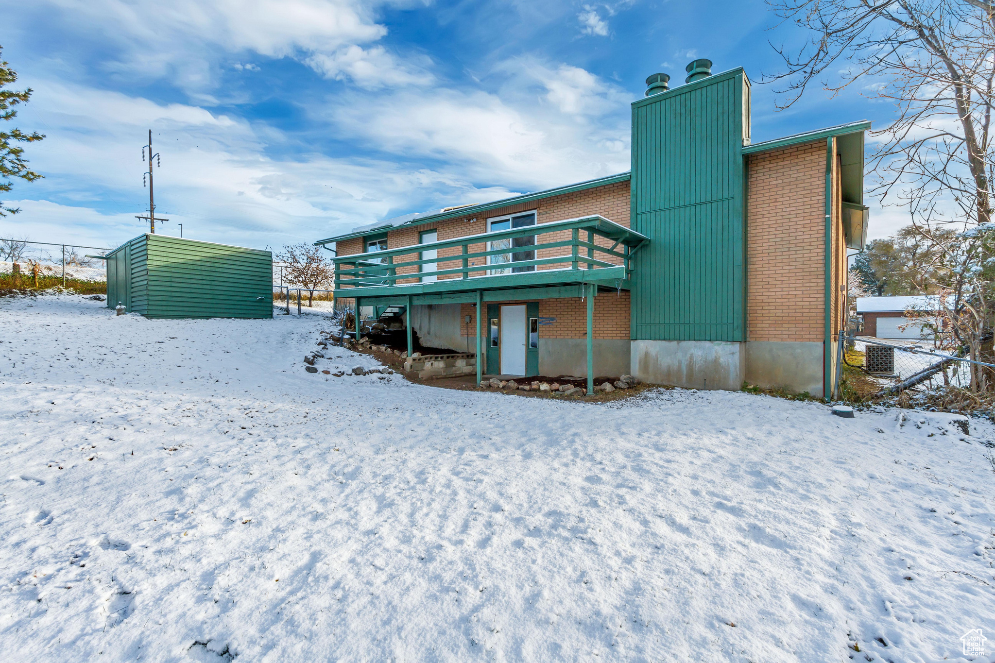 Snow covered rear of property featuring a deck