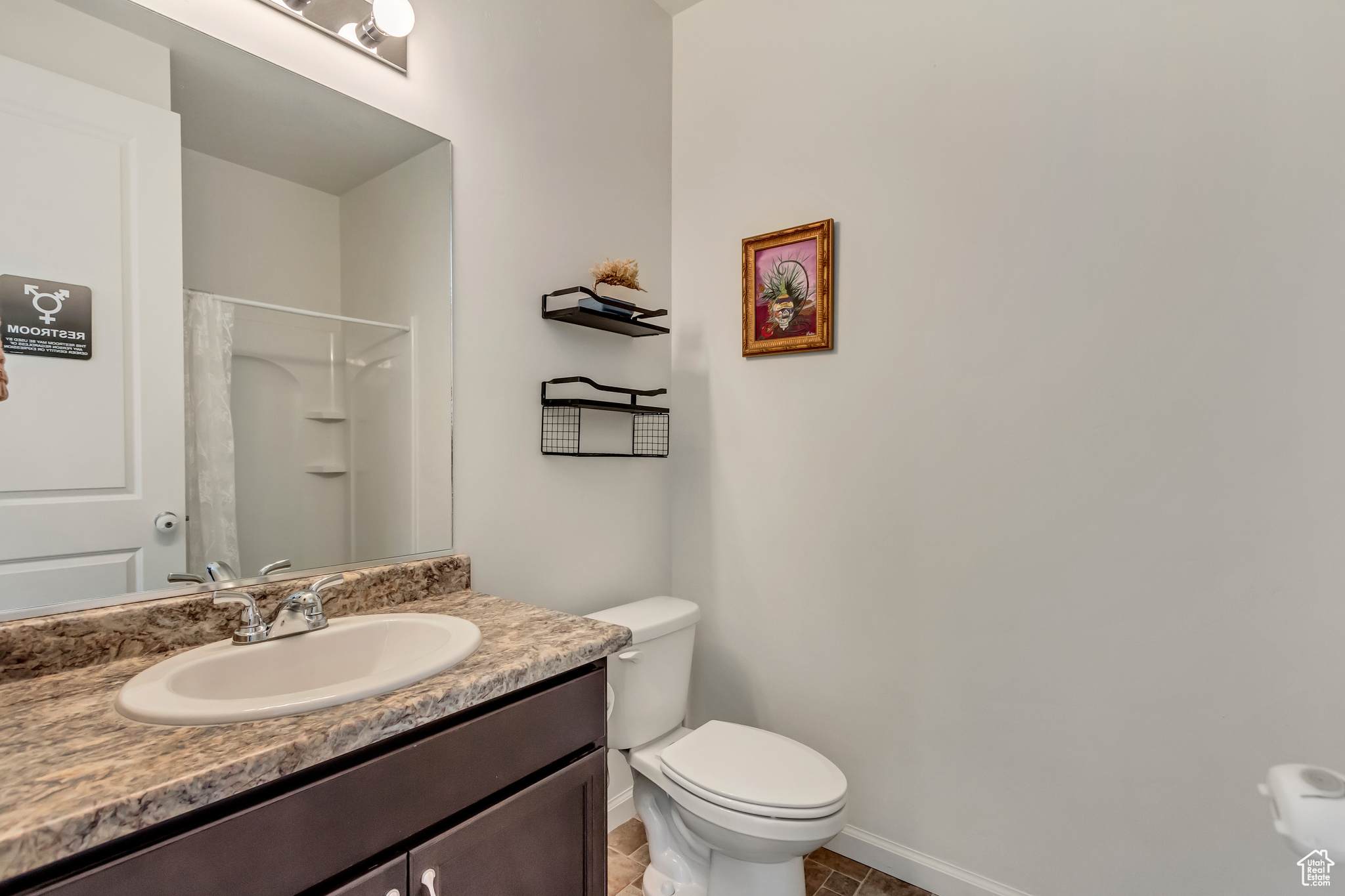 Bathroom featuring tile patterned floors, vanity, toilet, and walk in shower