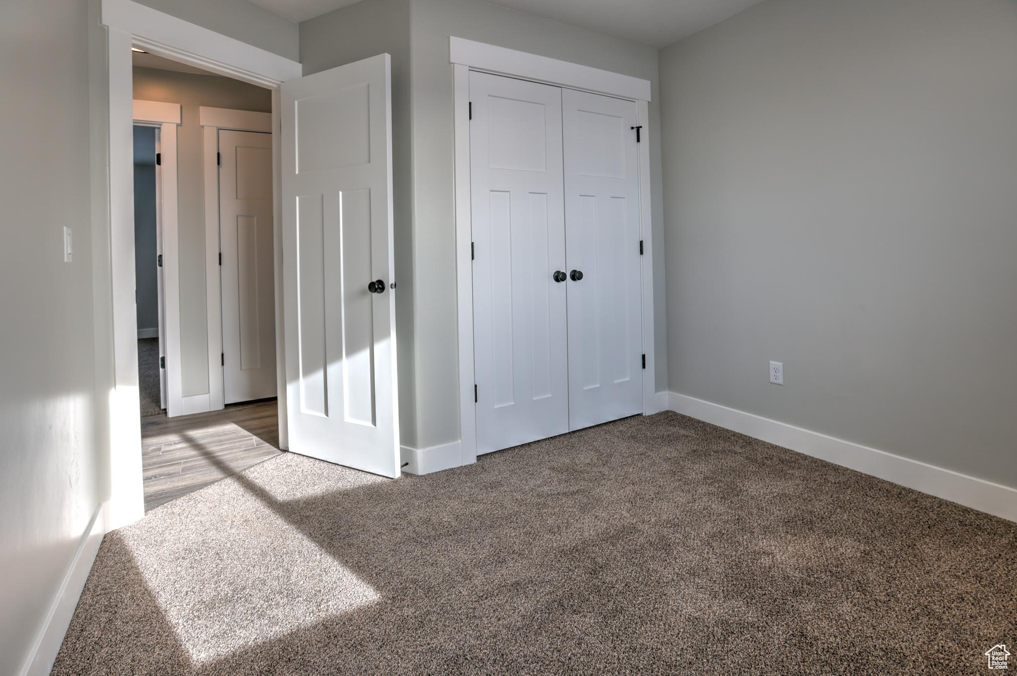 Unfurnished bedroom with light carpet and a closet