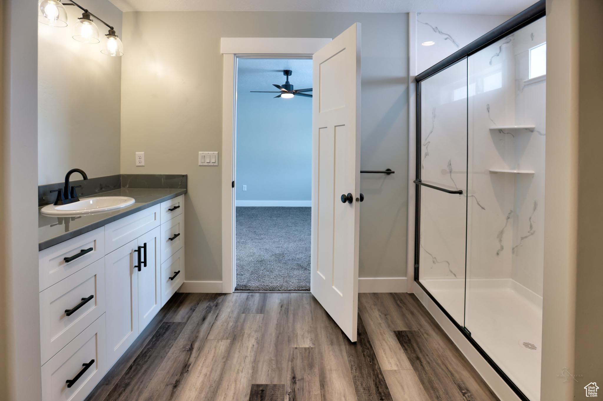 Master Bathroom with wood-type flooring, vanity, a shower with door, and ceiling fan