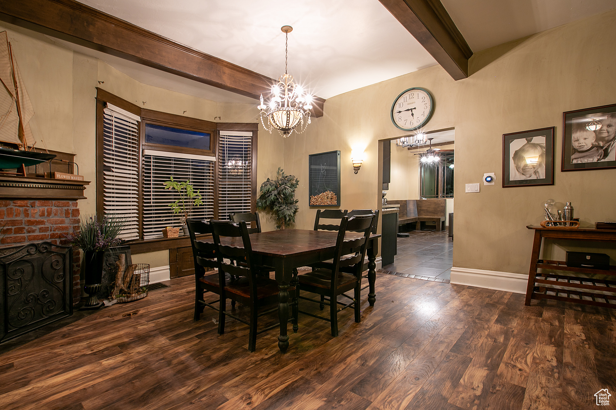 Dining area featuring beam ceiling, a chandelier, a fireplace, and dark wood-type flooring