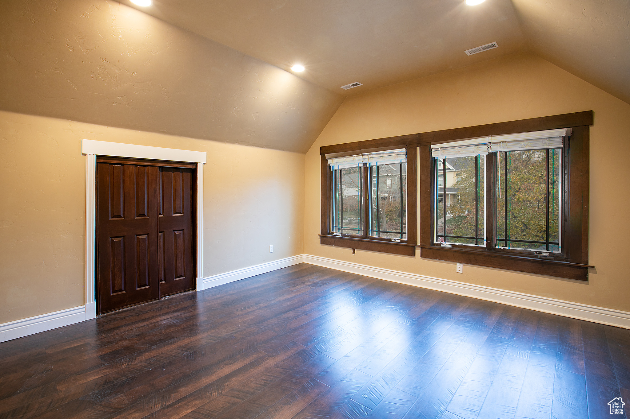 Bonus room with dark wood-type flooring and lofted ceiling