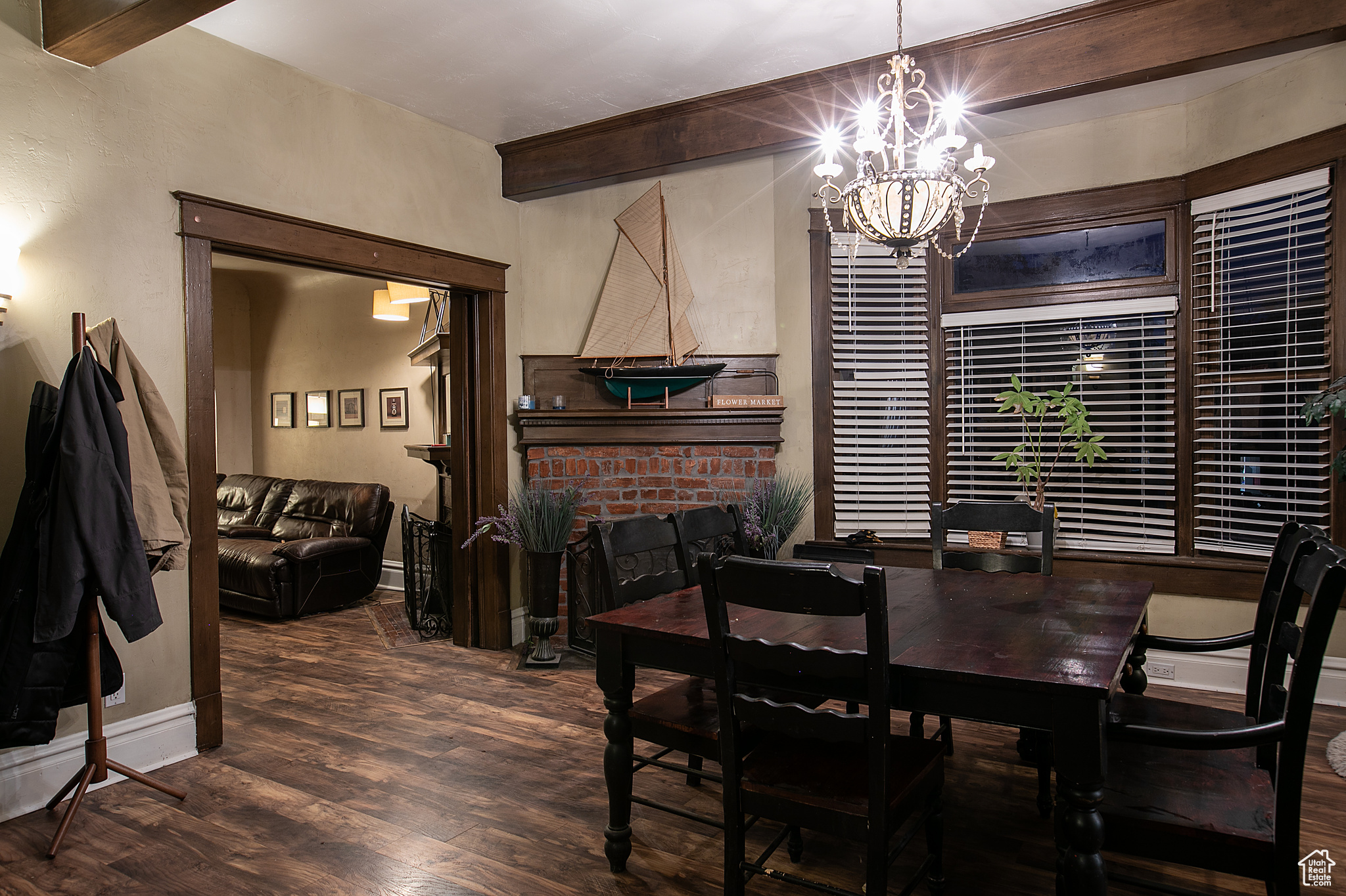 Dining space featuring a fireplace, beam ceiling, dark hardwood / wood-style flooring, and an inviting chandelier