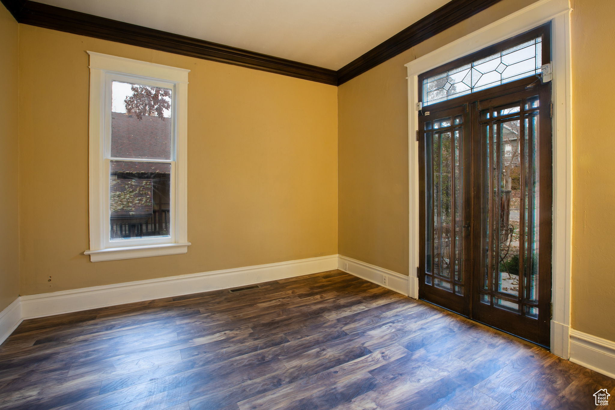 Entrance foyer with dark hardwood / wood-style flooring, ornamental molding, and french doors