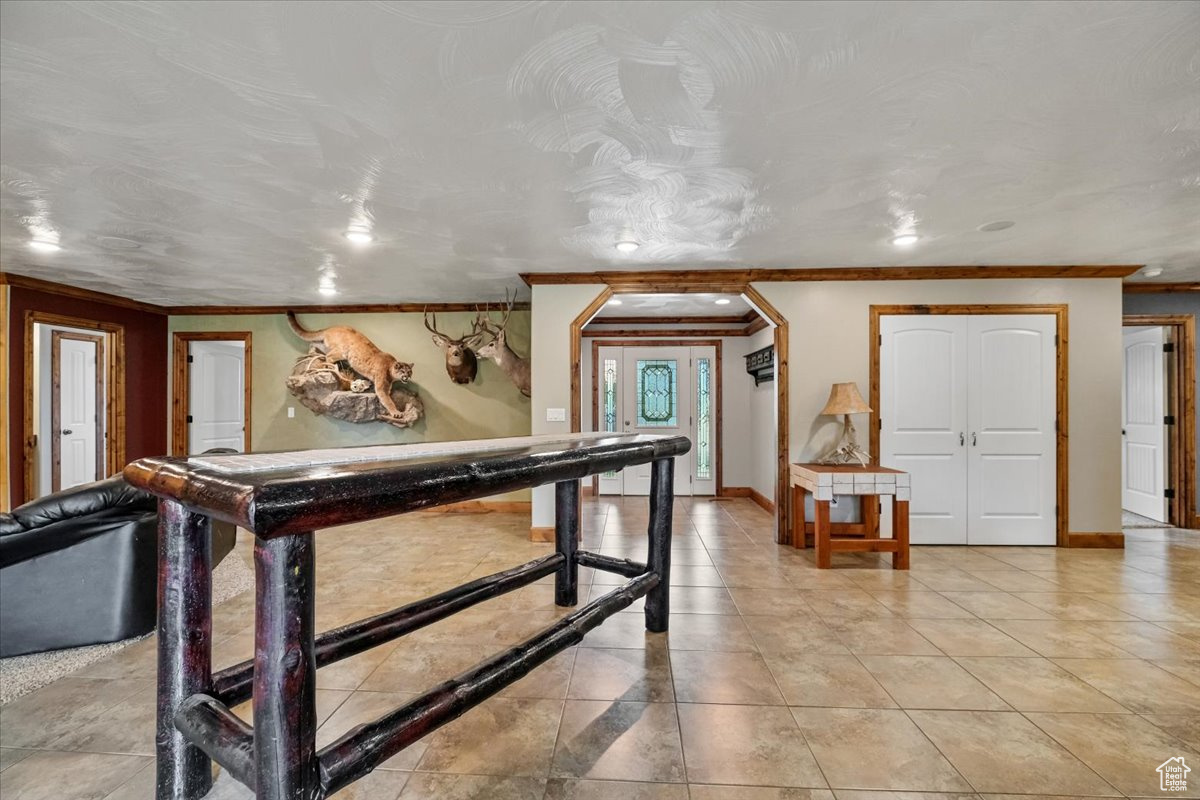 Rec room with light tile patterned floors and ornamental molding