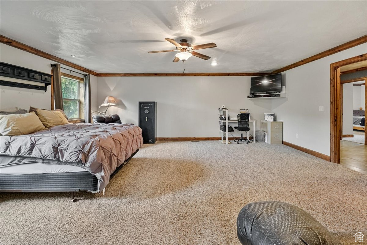 Bedroom with light carpet, ceiling fan, and crown molding