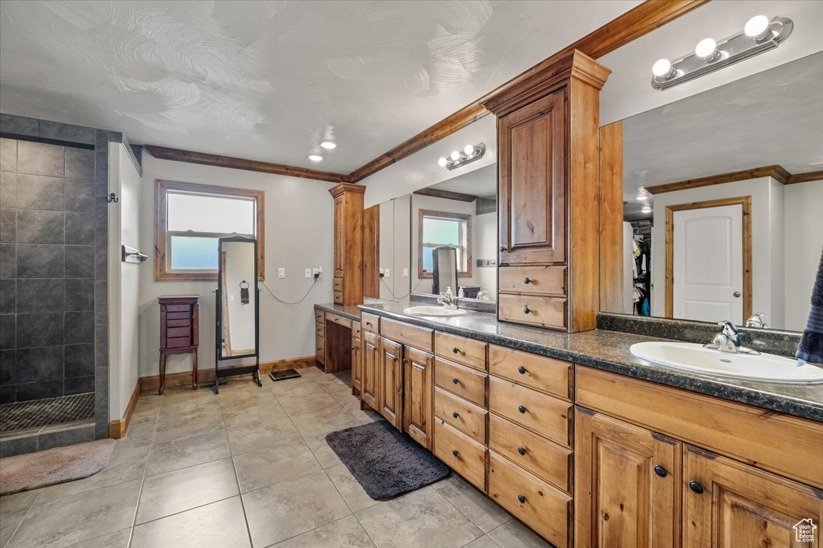 Bathroom featuring tile patterned floors, a shower, vanity, and ornamental molding