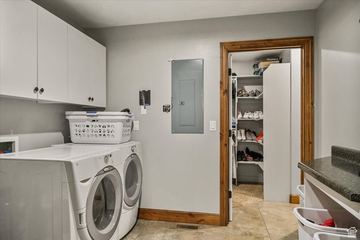 Laundry area with cabinets, washing machine and dryer, and electric panel