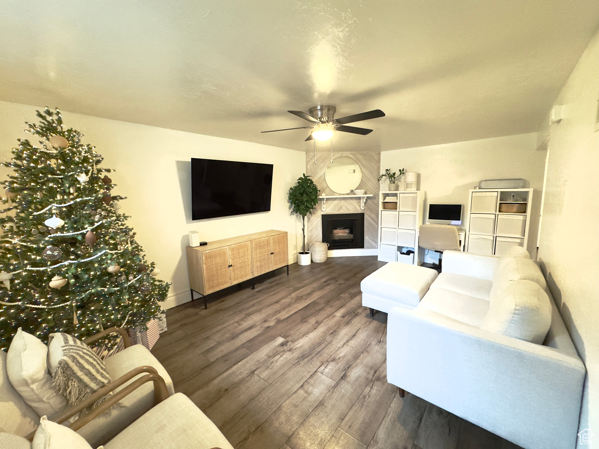 Living room with ceiling fan, dark hardwood / wood-style flooring, and a premium fireplace