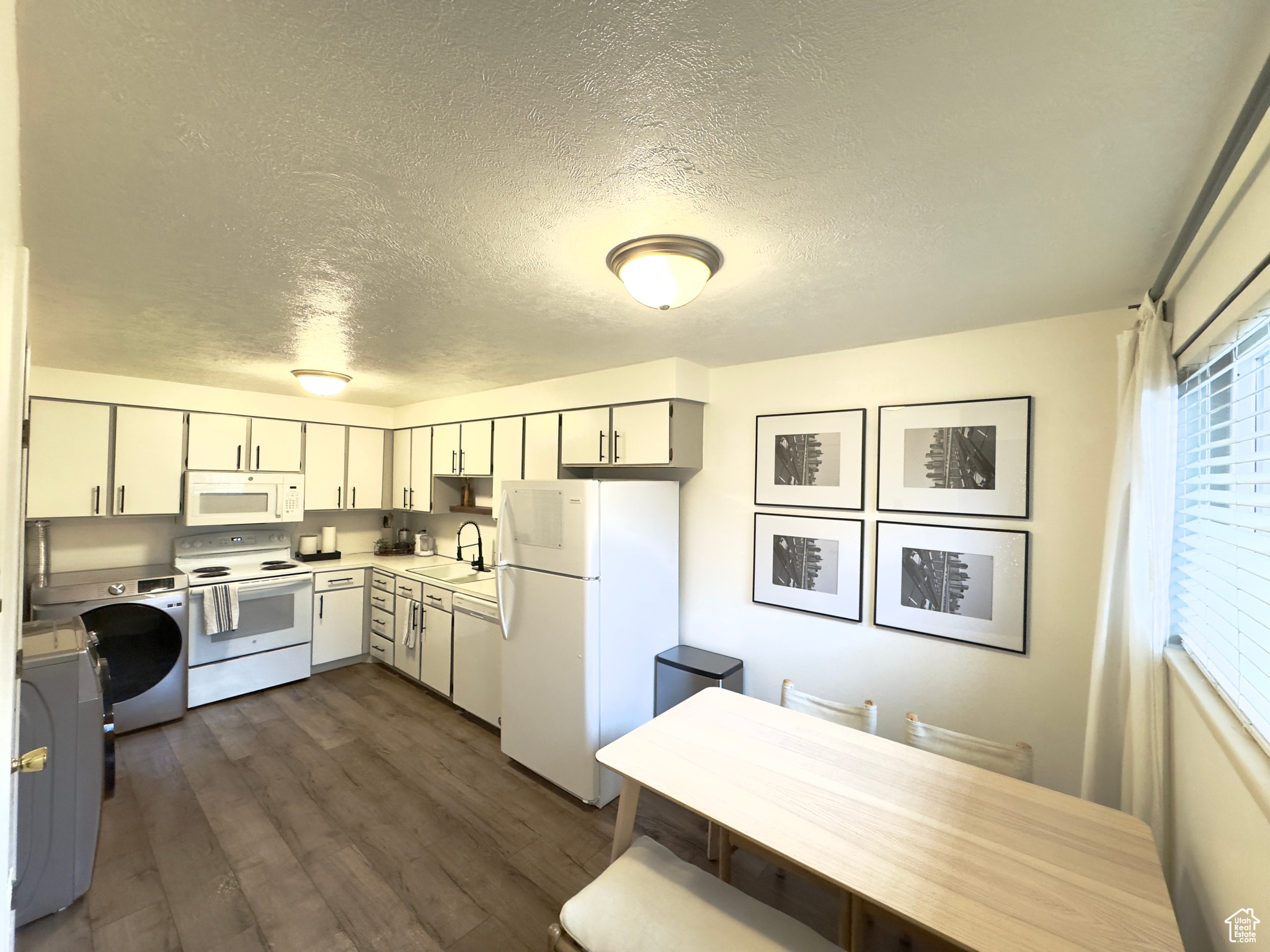 Kitchen with white appliances, dark wood-type flooring, sink, a textured ceiling, and washer / clothes dryer