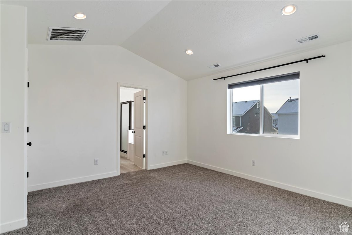 Unfurnished room with carpet flooring and lofted ceiling