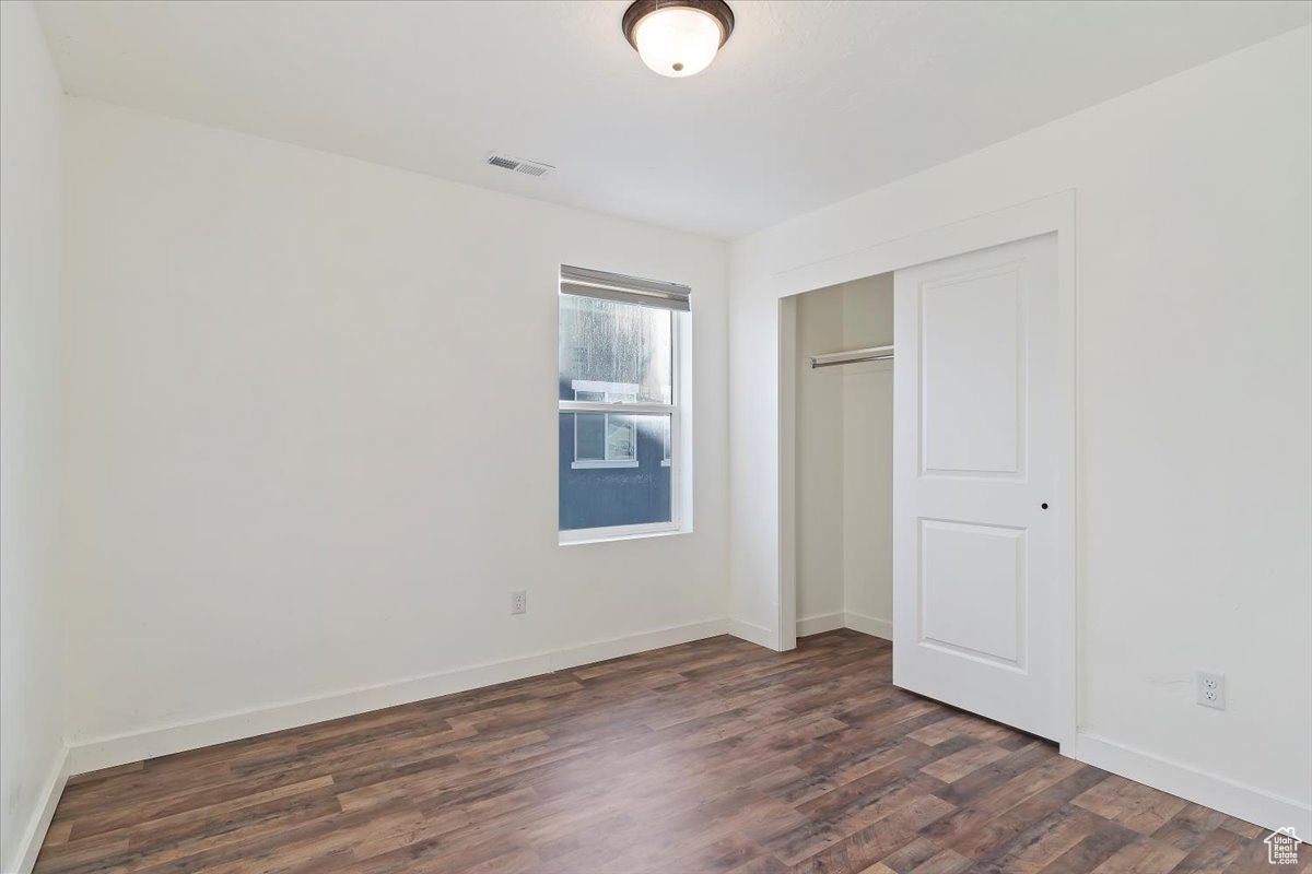 Unfurnished bedroom featuring a closet and dark hardwood / wood-style flooring