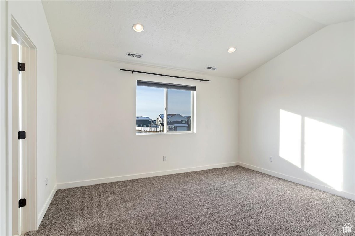 Carpeted spare room with lofted ceiling