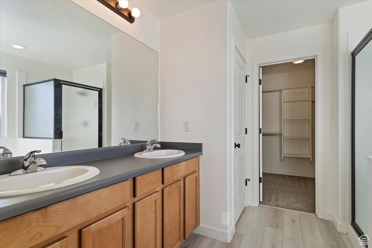 Bathroom with hardwood / wood-style floors, vanity, and a shower with door